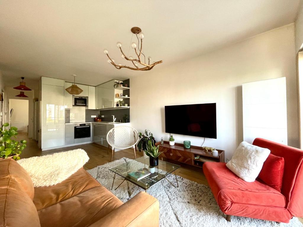 Il comprend un salon doté d'un canapé rouge et d'une télévision à écran plat. dans l'établissement Magnifique 3 pièces de 55m2 au calme avec balcon, à Paris
