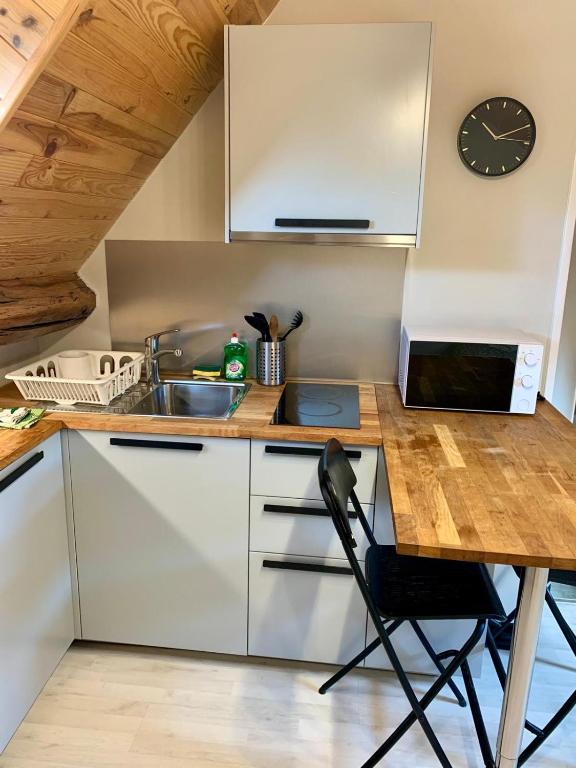 - une cuisine avec un comptoir, un évier et une horloge dans l'établissement Studio à louer à 1 h de Paris, à Montereau-faut-Yonne