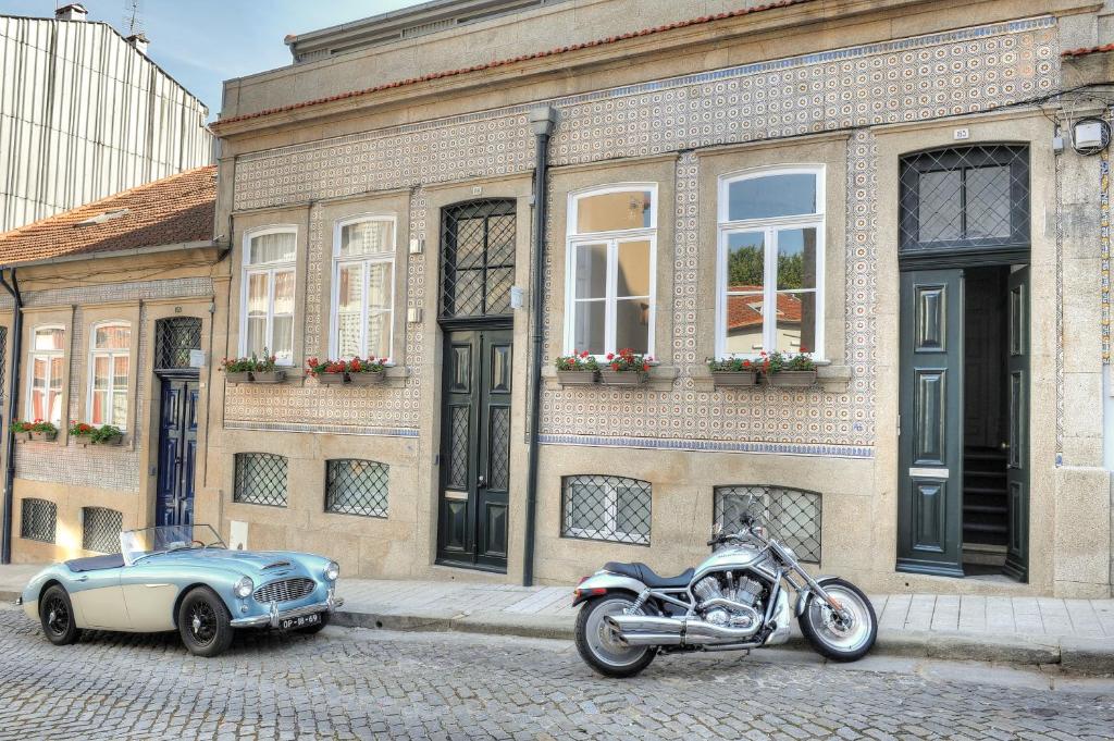 een motor en een auto geparkeerd voor een gebouw bij Three Houses & Bedrooms in Porto
