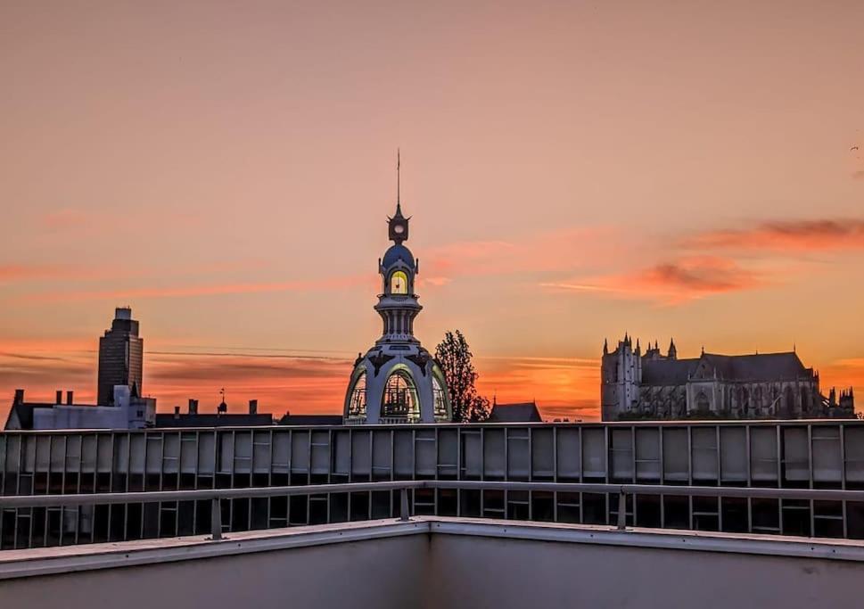 une tour d'horloge au sommet d'un immeuble avec un coucher de soleil dans l'établissement Biscuiterie Terrasse parking centre ville, à Nantes