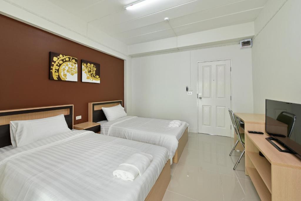 a hotel room with two beds and a flat screen tv at B32 Apartment in Bangna