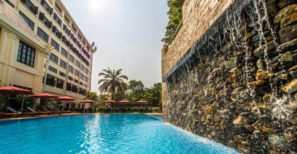 a swimming pool in front of a building at Rose Garden Hotel in Yangon