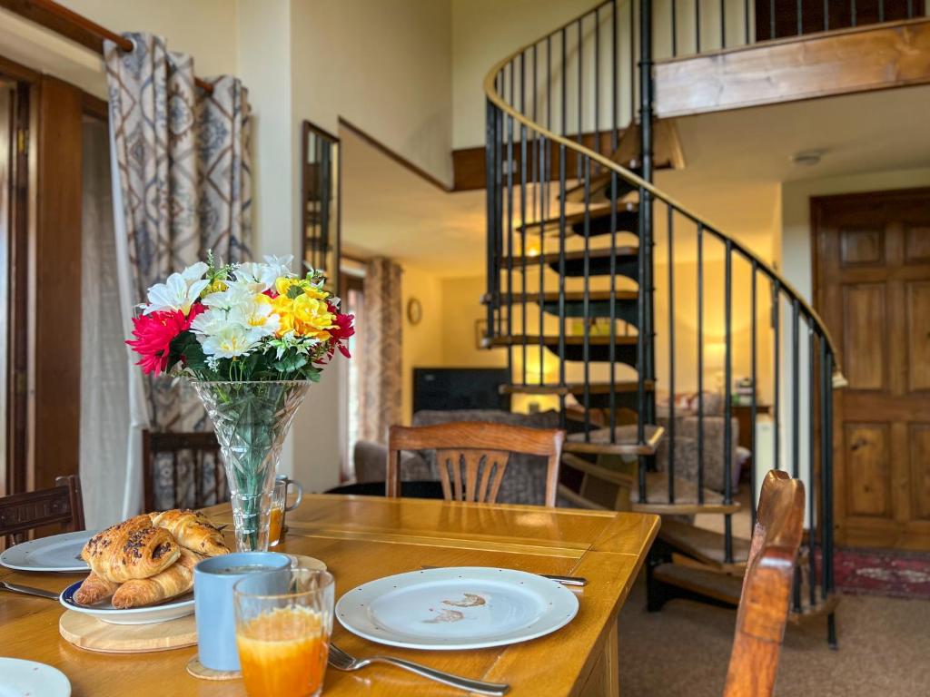 a dining room table with a vase of flowers on it at Tarnside Cottages in Brampton
