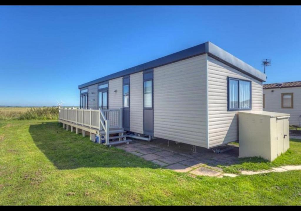 a mobile home in a yard next to a field at MP502 - Camber Sands Holiday Park - Sleeps 6 - Small Dog - Gated Decking - Amazing Marsh Views in Camber
