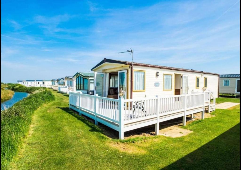 a row of cottages on the shore of a river at MP503 - Camber Sands Holiday Park - Sleeps 8 - Large Gated Decking - Amazing views in Camber