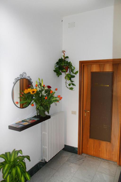 a hallway with a door and a mirror and flowers at B&B Music in Milan