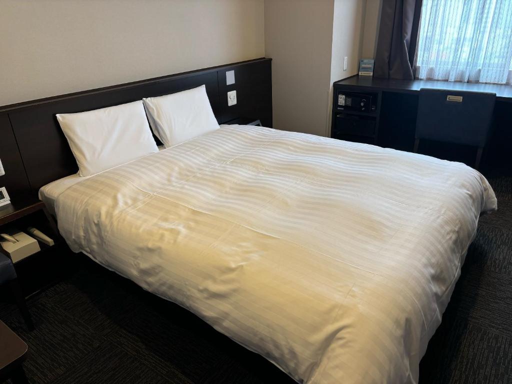 Postel nebo postele na pokoji v ubytování Dormy Inn Kochi