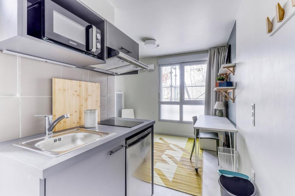 une cuisine blanche avec un évier et une fenêtre dans l'établissement Student Factory Clermont République, à Clermont-Ferrand
