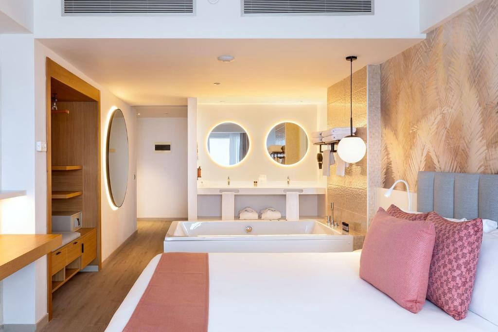 a bedroom with a large white bed and a tub at Hotel Cristina by Tigotan Las Palmas - Adults Only in Las Palmas de Gran Canaria