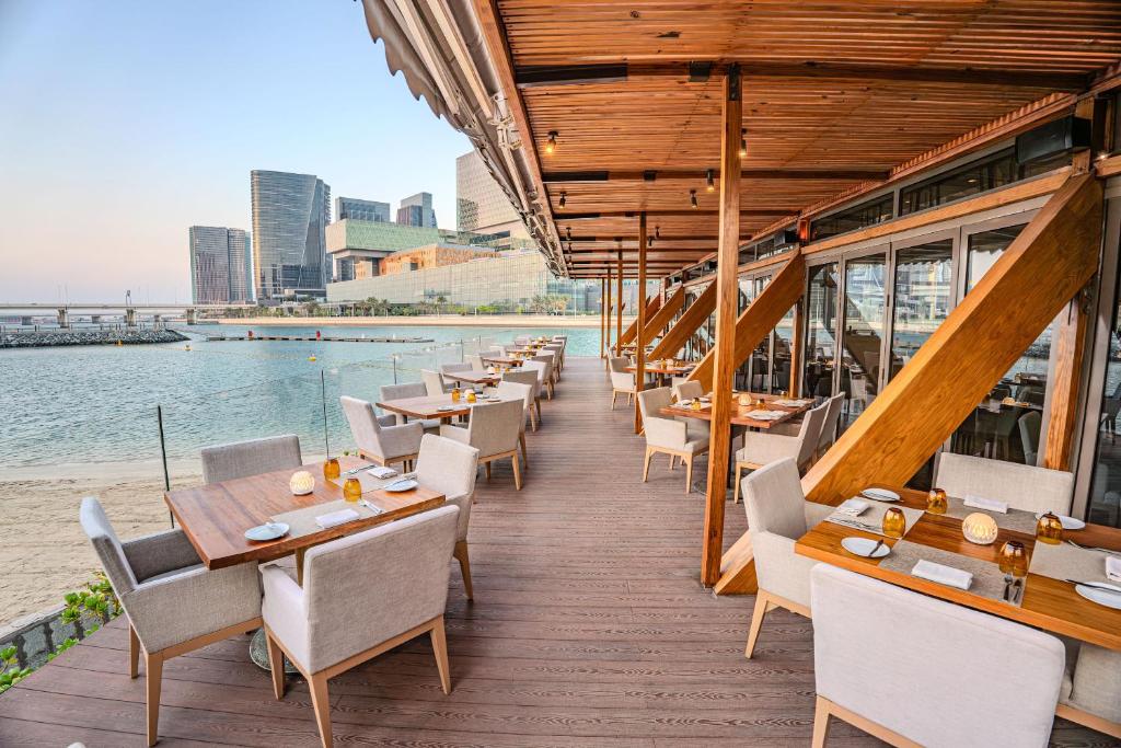 a row of tables and chairs on the deck of a restaurant at Beach Rotana - Abu Dhabi in Abu Dhabi