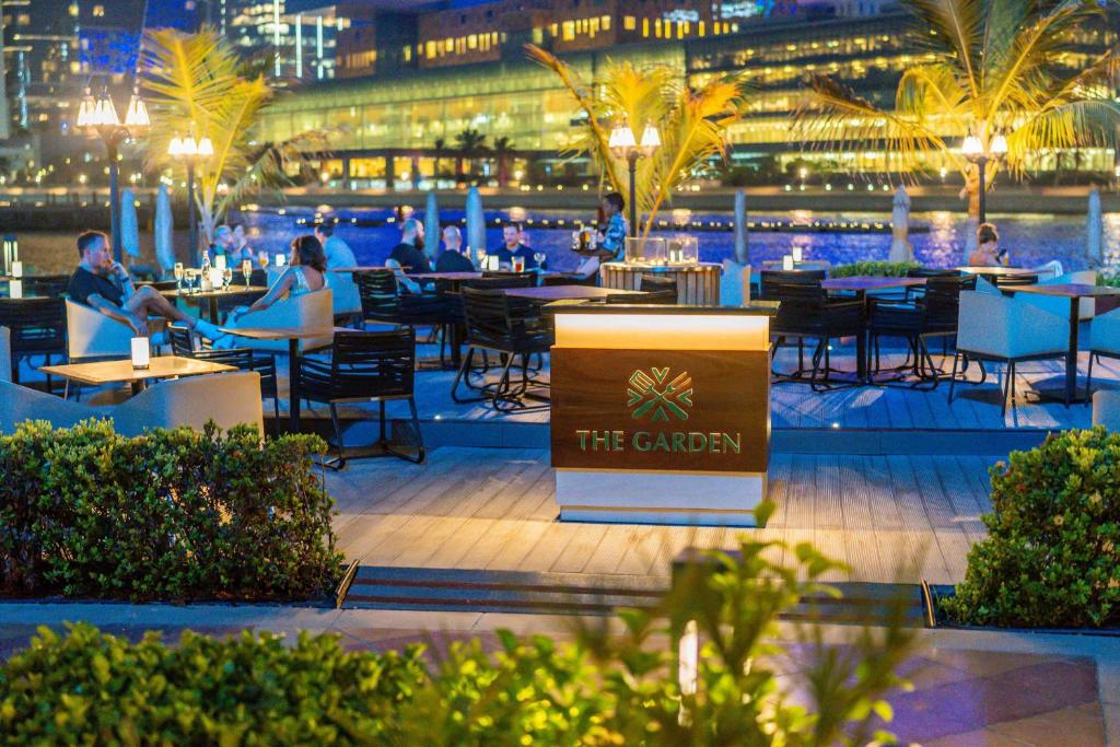 a restaurant with people sitting at tables at night at Beach Rotana - Abu Dhabi in Abu Dhabi