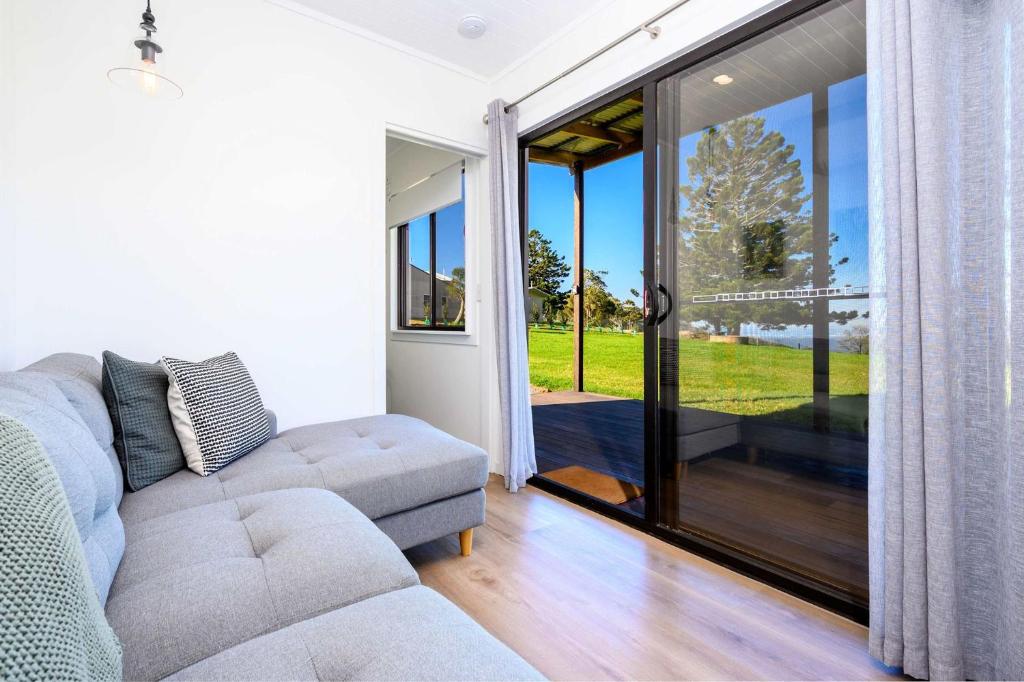 a living room with a couch and a sliding glass door at Three Pines Tiny Home Your Mountain Escape in Mount Tamborine