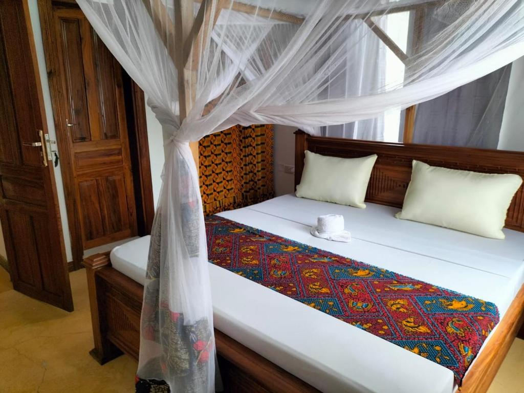 a bedroom with a bed with a canopy at Tumbo Swahili Villa in Gulioni