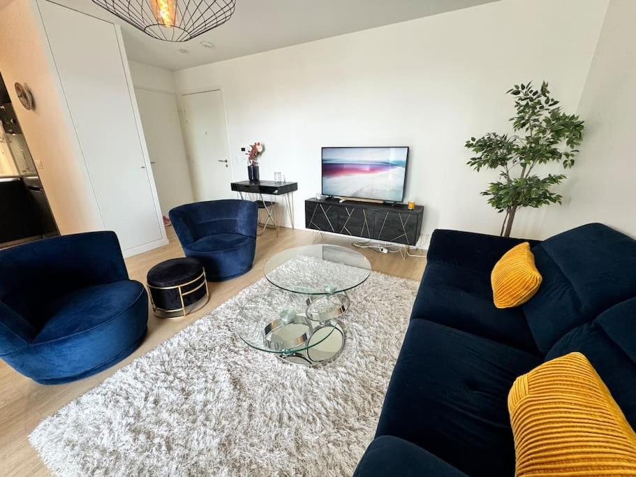 un salon avec un canapé bleu et une table dans l'établissement Cosy moderne 2 pièces - balcon - Asnières - 2 PAX, à Asnières-sur-Seine