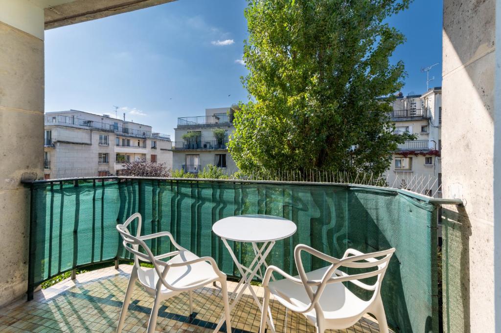 une table et des chaises sur le balcon d'un bâtiment dans l'établissement Spacious 3BD Family Apartment Auteuil, à Paris