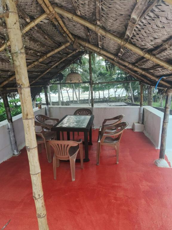 坎努尔Raaga on the Beach的红色地板的房间的桌椅