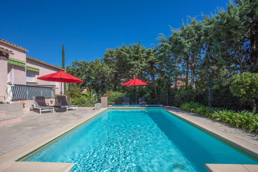 - une piscine avec des parasols rouges dans une cour dans l'établissement Coin de paradis plage Peguiere, à Saint-Raphaël