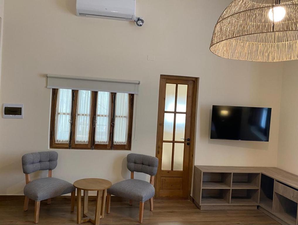 a living room with two chairs and a table and a tv at Posada del Milagro in Salta