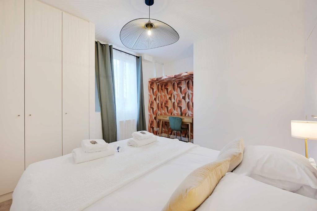une chambre avec un lit blanc avec des serviettes dessus dans l'établissement Cosy apartment - 1BDR-4P - Boulogne Billancourt, à Boulogne-Billancourt