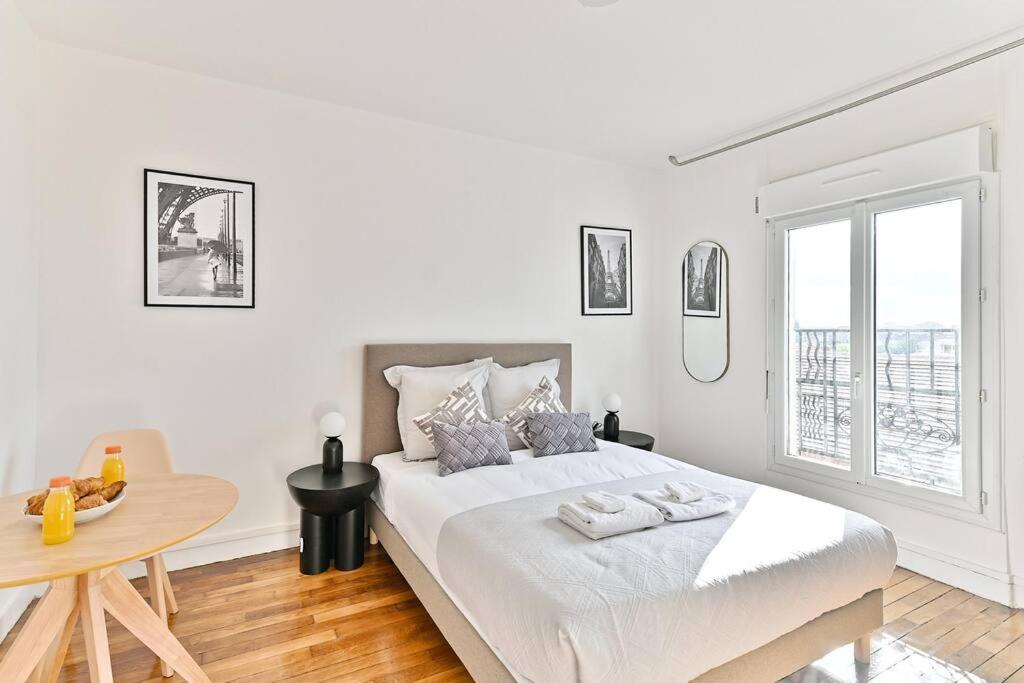 une chambre blanche avec un grand lit et une table dans l'établissement Studio confortable Havre de Paix proche Paris - II, à Montreuil