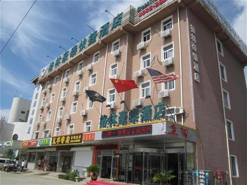 威海市にあるGreenTree Inn Shandong Weihai Bus Station Express Hotelの旗の目の前の大きな建物