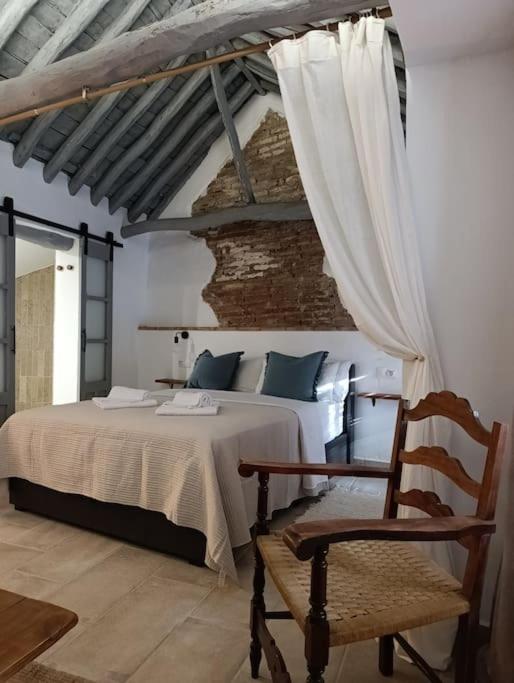 a bedroom with a white bed and a chair at El Capricho in Ronda