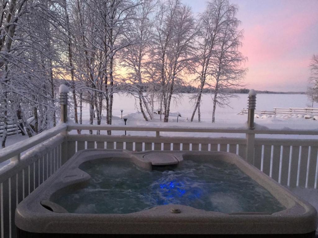 Nellim Holiday Home في Nellimö: حوض استحمام ساخن في الثلج على السياج