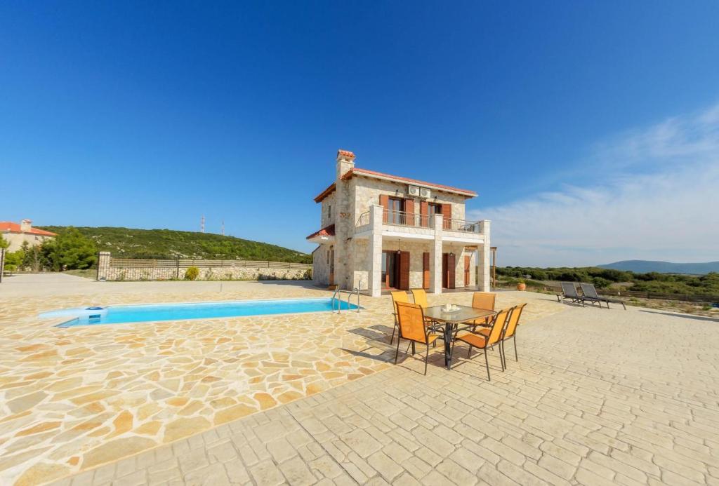 a house with a table and chairs next to a pool at Sunset Vista Villas Classic II in Volímai