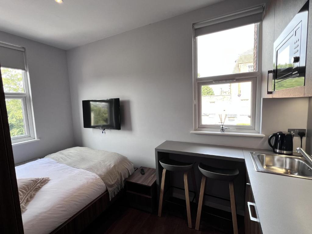 a bedroom with a bed and a kitchen with a sink at London Studio Retreat - Colney Hatch Lane in London