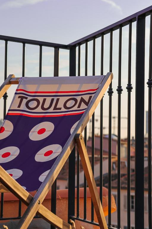 a wooden chair with a coliseum sign sitting on a balcony at L'Eautel Toulon Centre Port in Toulon