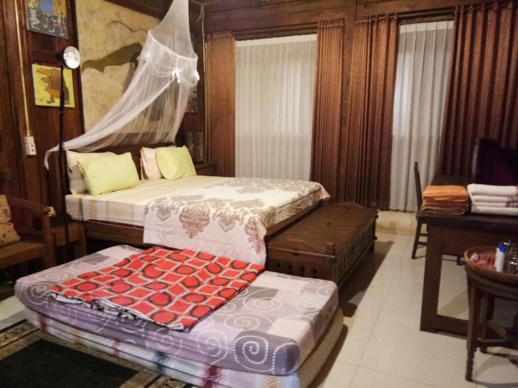 ein Schlafzimmer mit 2 Betten und einer Bank darin in der Unterkunft Kampung Baron Cottage in Yogyakarta