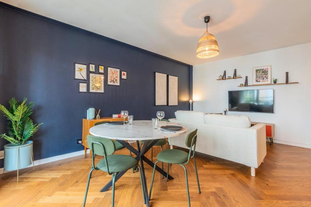 une salle à manger avec une table blanche et des chaises vertes dans l'établissement Bel appartement bien situé avec balcon et parking, à Lille