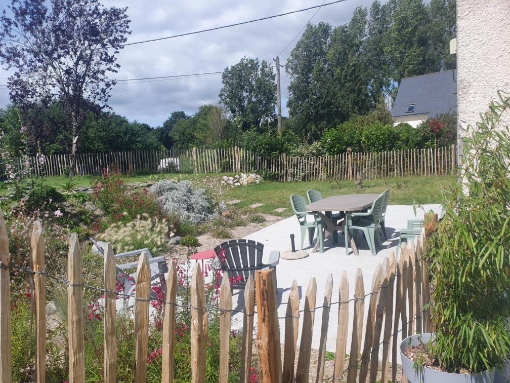 une clôture avec des chaises et une table dans la cour dans l'établissement Gîte Au Cerisier, à Plouégat-Guérand