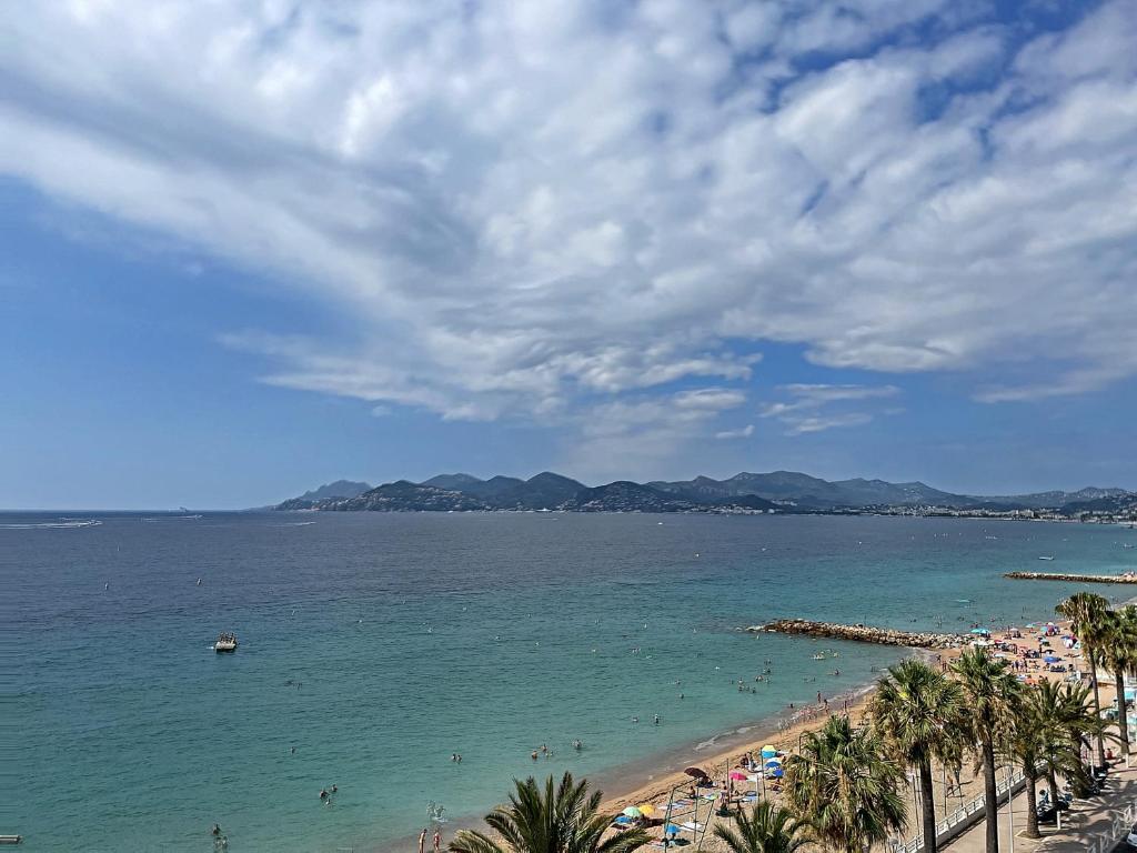 une plage avec des gens dans l'eau et des palmiers dans l'établissement Superbe 3 pièces front de mer 303L MEGR, à Cannes