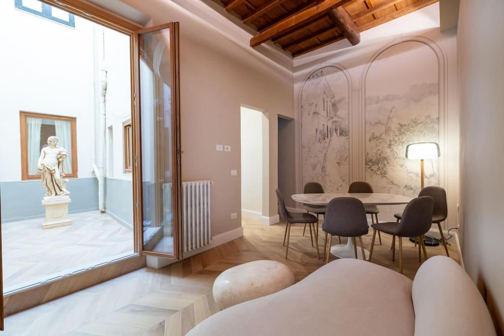 una sala de estar con mesa, sillas y una estatua en Casa Bacco, en Florencia