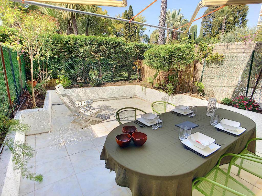 une table en bois assise sur une terrasse avec des chaises dans l'établissement Superbe 3 pièces RDJ à 2 pas des plages 295L, à Cannes