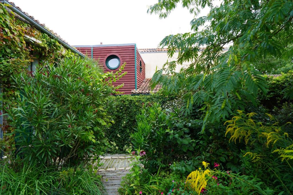 a house with a garden with plants and trees at Maison du chat bleu in Saint-Hilaire-de-Clisson