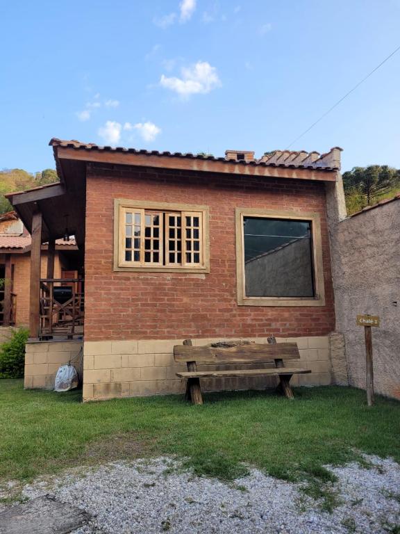 a wooden bench sitting in front of a house at Chalés das cerejeiras in Santo Antônio do Pinhal