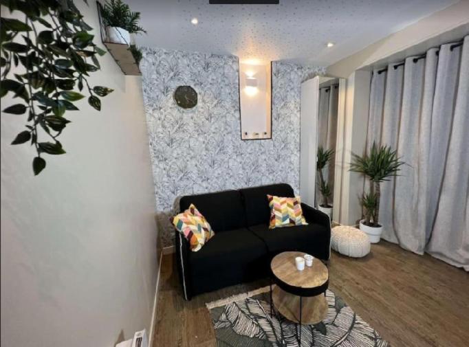 un salon avec un canapé noir et une table dans l'établissement la cale à la mer, à Dieppe