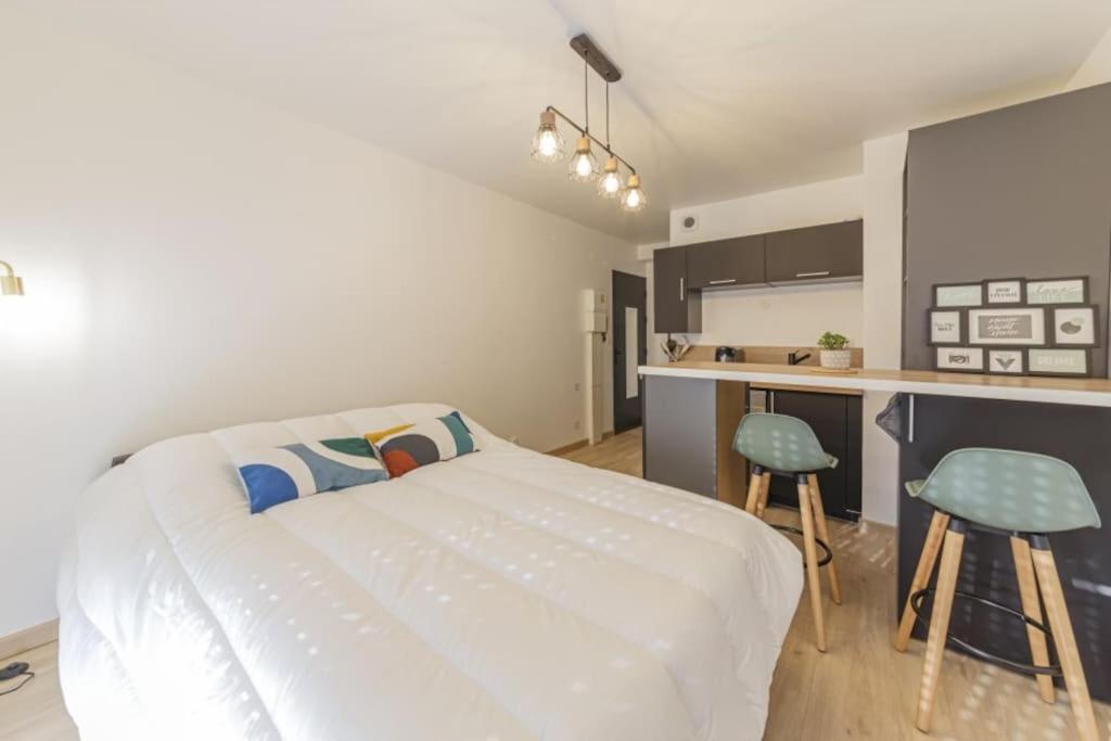 Cet appartement comprend une chambre avec un lit et une cuisine avec des tabourets. dans l'établissement Le Studio Gare, à Rennes