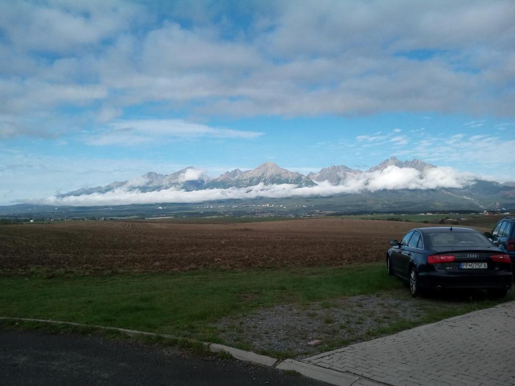 a car parked on the side of a road with mountains at Hotel Premiér Poprad 13 Jeseň vo Vysokých Tatrách in Poprad
