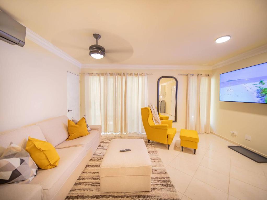 ソスアにあるGarden Condos 21, Modern 1BR APT In Sosua Strip GUEST FRIENDLYのリビングルーム(白いソファ、黄色の椅子付)