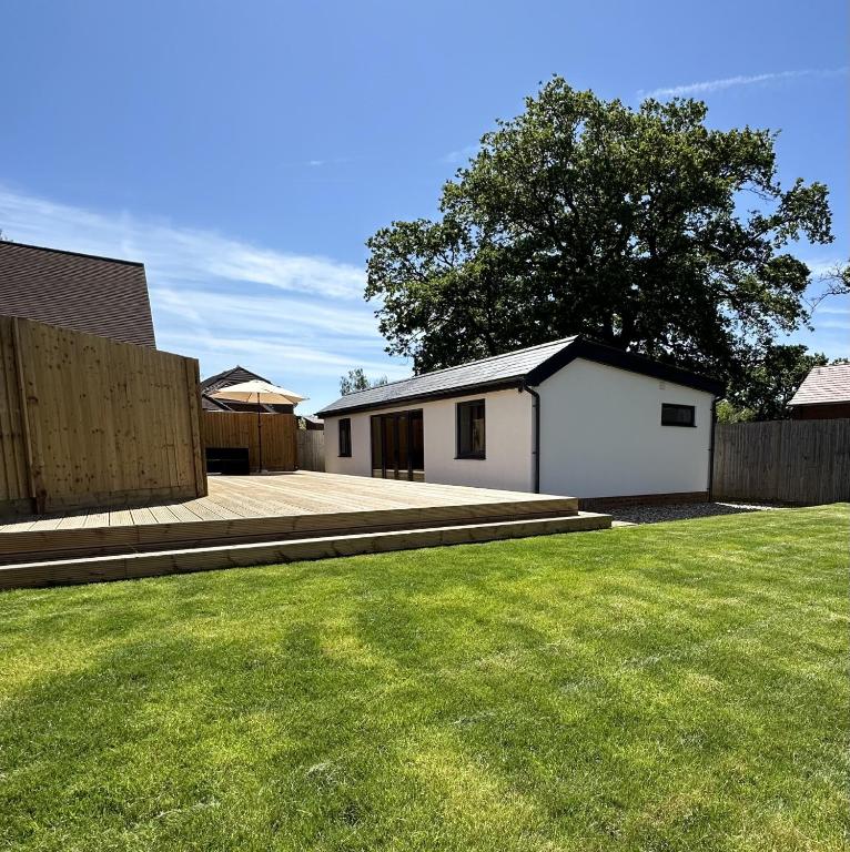a yard with a white house and a fence at White Oaks Sussex in Twineham