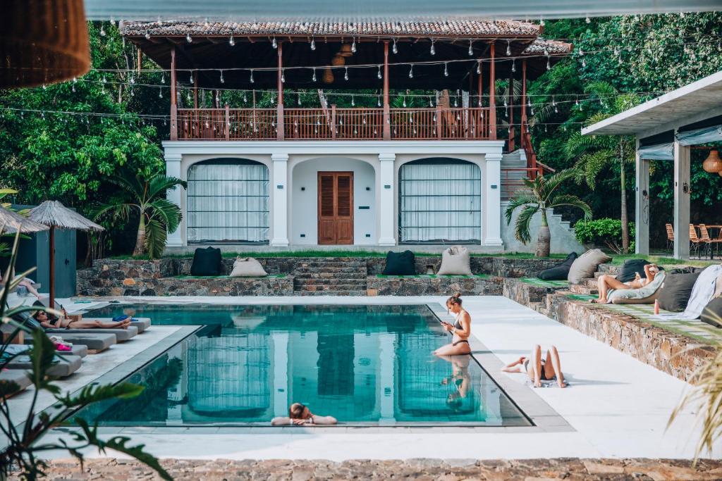 a pool in front of a house with people in it at The Salty Pelican Yoga & Surf Retreat in Dickwella