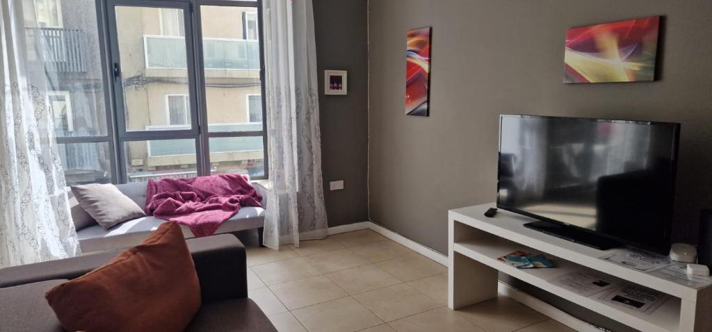 un soggiorno con divano, TV e finestra di PACEVILLE St Julians Apartments a San Giuliano