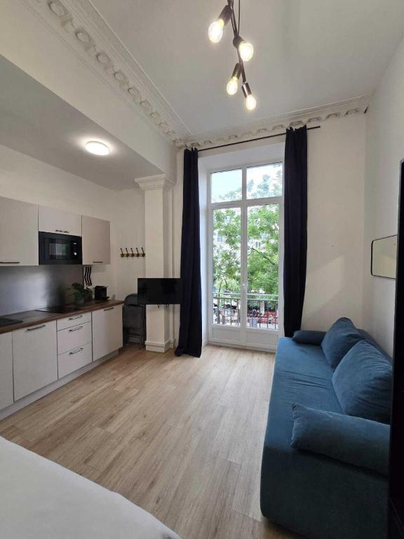 un salon avec un canapé bleu et une cuisine dans l'établissement Studio Opera, à Paris