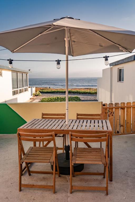 a wooden table and two chairs under an umbrella at CASA TUCAN - BEACH JUNGLE PARADISE in Ensenada
