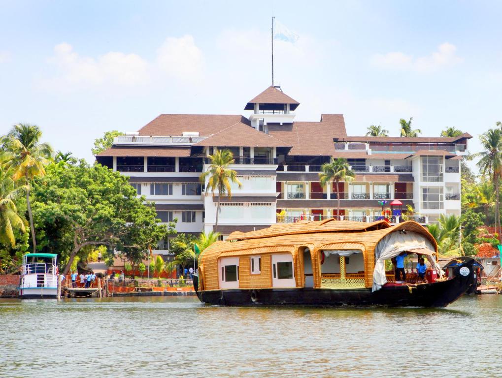 a house boat in the water in front of a building at Hotel All Season in Kollam