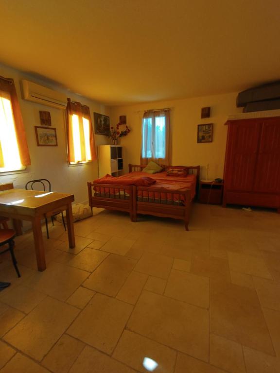 une chambre avec un lit, une table et des fenêtres dans l'établissement Luberon sud, à La Bastidonne