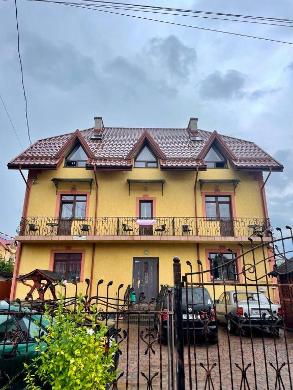a yellow house with cars parked in front of it at Вілла Львів in Skhidnitsa